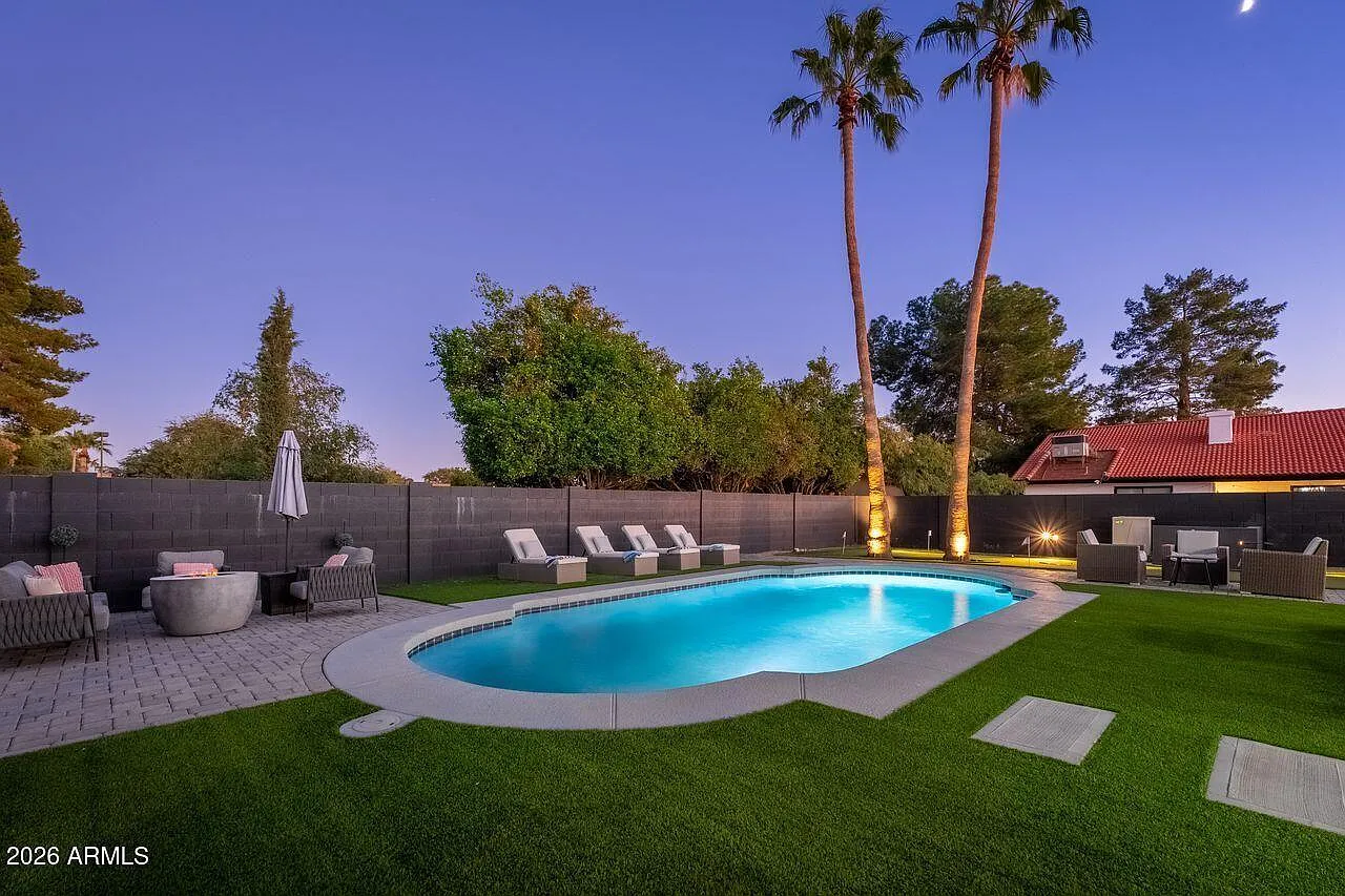 Heated pool with lounge, firepit, and palms