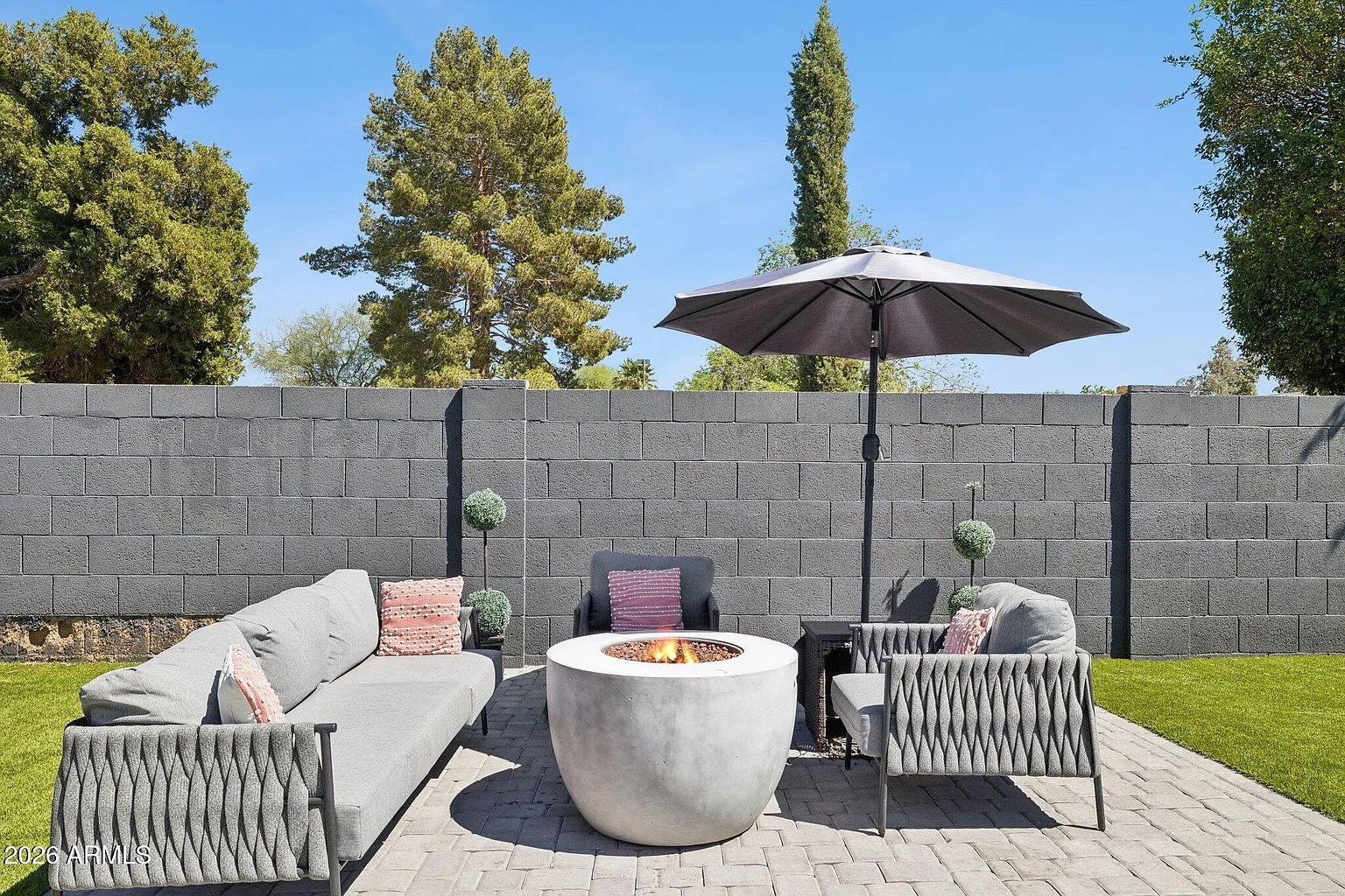 Concrete firepit with woven lounge under a market umbrella